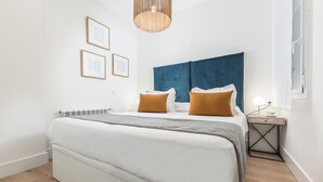 A bedroom with a bed, a bedside table with a lamp, and framed pictures on the wall. - Doctor Castelo LXIV - Two Bedroom Apartment, Sleeps 3 (Madrid)