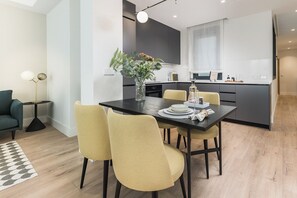 A modern kitchen with a dining area, a small side table, and a sofa. - Doctor Castelo LXIII (Madrid)