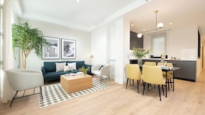 Een moderne woonkamer met een bank, salontafel en een eethoek met stoelen.