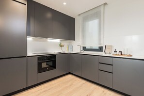 A modern kitchen with grey cabinetry, a built-in oven, and a window above the sink. - Doctor Castelo LXIII (Madrid)