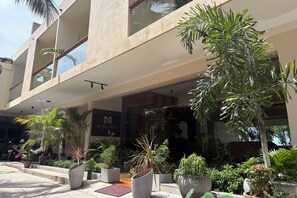 A hotel with a modern facade, multiple balconies, and a variety of potted plants. - Mora Mila (Arugam Bay)