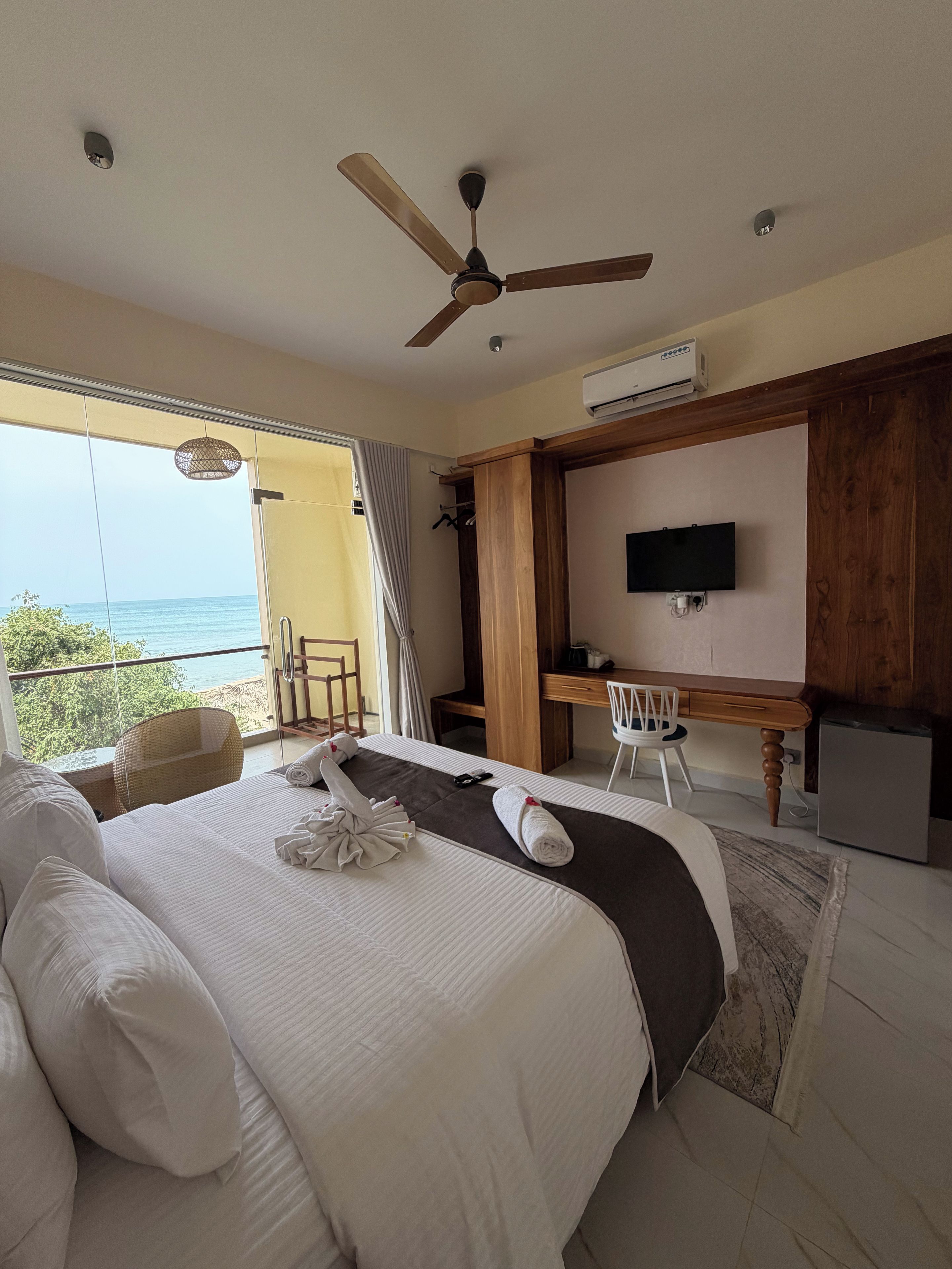 Habitación de hotel con cama, escritorio, silla, televisión y vista al mar.