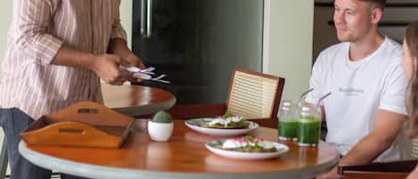 Una mesa de comedor con platos de comida, una planta pequeña y una bebida.