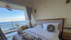 A hotel room with a bed, a view of the beach, and a balcony. - Mora Mila (Arugam Bay)