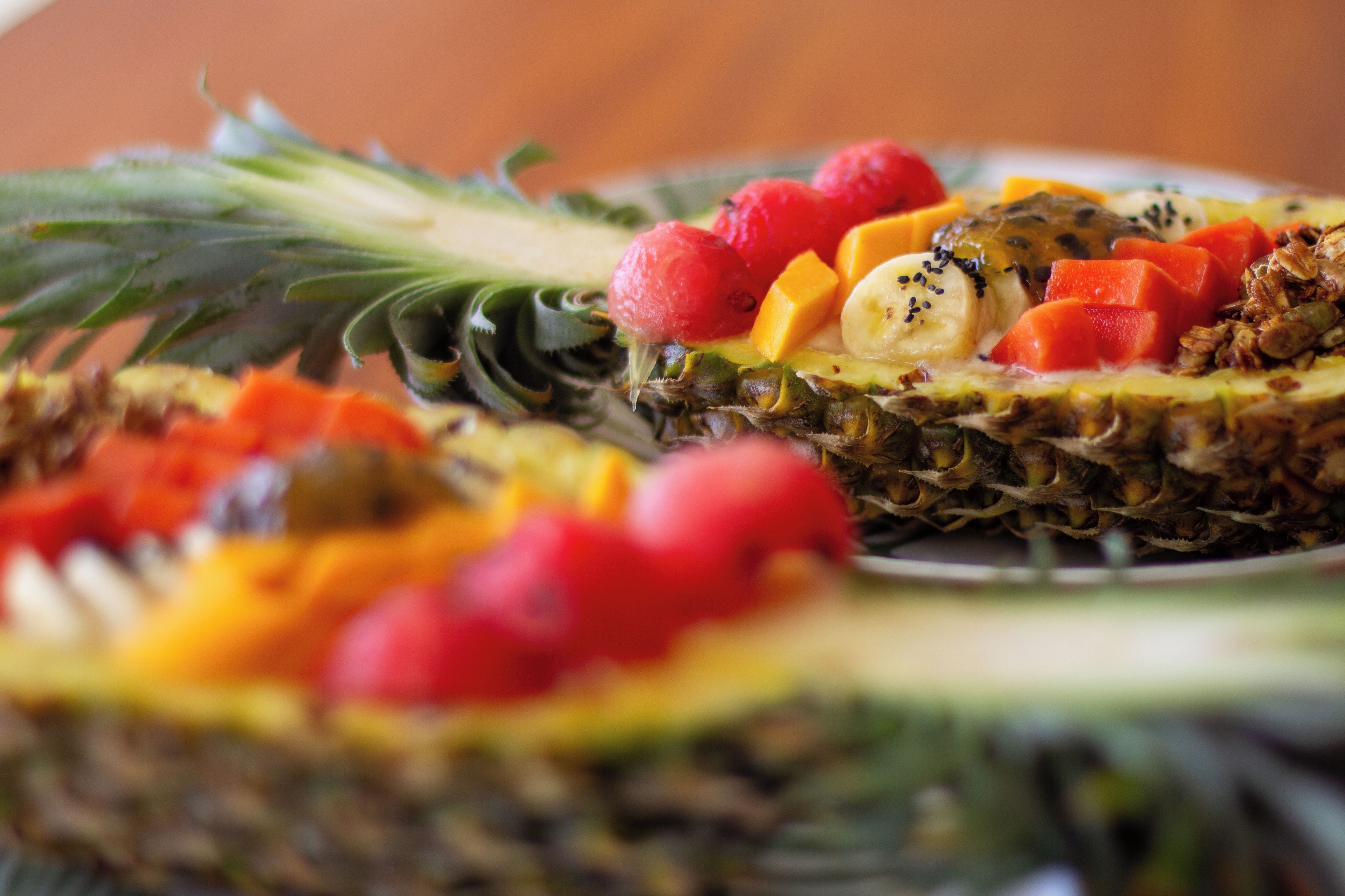Ein Teller mit verschiedenen Früchten, darunter Ananas, Mango und Himbeeren.