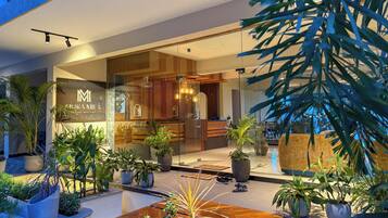 A modern hotel lobby with a reception desk, seating area, and potted plants.