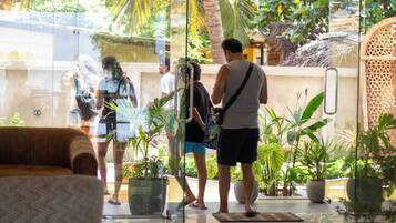 A glass-walled lobby with indoor plants, a seating area, and a visible outdoor view.