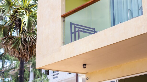 A modern building with a balcony, a palm tree, and a clear sky. - Mora Mila (Arugam Bay)