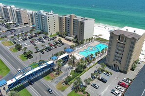 A hotel with a swimming pool, a parking lot, and a view of the beach. - Beach View Top Floor Condo | Skywalk Beach Access | Pools | Sleeps 6 | BEACHBALL PROPERTIES (Gulf Shores)