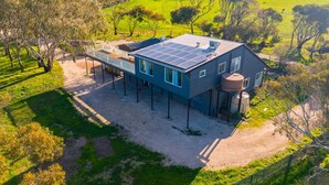 Una casa moderna con tetto solare, serbatoio d'acqua e giardino recintato.