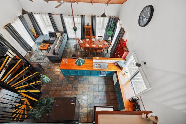 Un espacio de sala-comedor abierto y amplio, con techos altos, cocina, mesa de comedor y asientos.