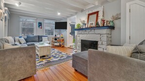 Una sala de estar con chimenea, un sofá, una mesa de centro y un televisor.