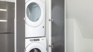 A front-loading washing machine in a utility room with a stainless steel door and a visible control panel. - Downtown Luxury 1BR Loft · Walkable · Sleeps 4 (Milwaukee)