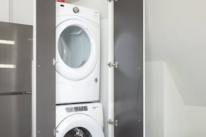 Een voorlader wasmachine in een technische ruimte, met een deur van roestvrij staal en een zichtbare bedieningspaneel.