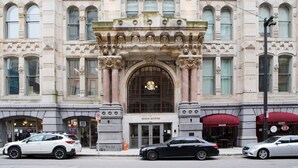 A historic building with ornate architecture, a central entrance, and storefronts including a bakery and a salon. - Downtown Luxury 1BR Loft · Walkable · Sleeps 4 (Milwaukee)