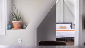 A modern hotel room with a bed, a potted plant, a book, and a kettle on a shelf. - Downtown Luxury 1BR Loft · Walkable · Sleeps 4 (Milwaukee)
