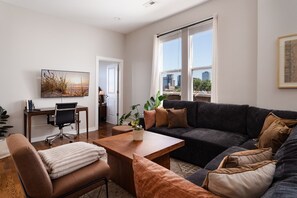 A living room with a sofa, coffee table, and a desk with a chair.