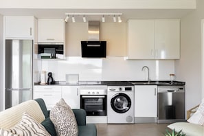 A modern kitchen with built-in appliances, a dining area with a sofa, and a living room with a coffee table. - Balcon del Mar - 2 bedroom - Nerja (Nerja)