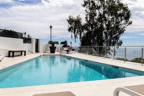 A rectangular swimming pool with a clear blue water, surrounded by a white deck, and a metal railing. - Balcon del Mar - 2 bedroom - Nerja (Nerja)
