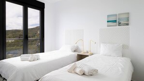 Ein Hotelzimmer mit zwei Betten, einem großen Fenster und Blick auf die Landschaft.