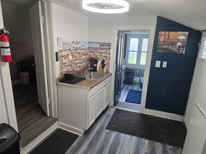 A compact kitchen with a stone backsplash, a sink, and a small countertop. - Lakefront Gem - Free Boat Launch: 2BR Paradise - Walk to Beach & Fish Lake Erie! (Lorain)