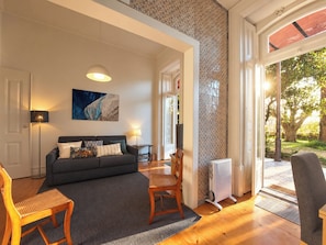 A modern living room with a sofa, chairs, a coffee table, and a large window providing a view of the outdoors. - Lisbon Hideaway with private sunny Garden (Lisbon)