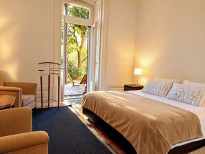 A hotel room with a bed, a chair, a small table, a lamp, and a view of the outdoors. - Lisbon Hideaway with private sunny Garden (Lisbon)
