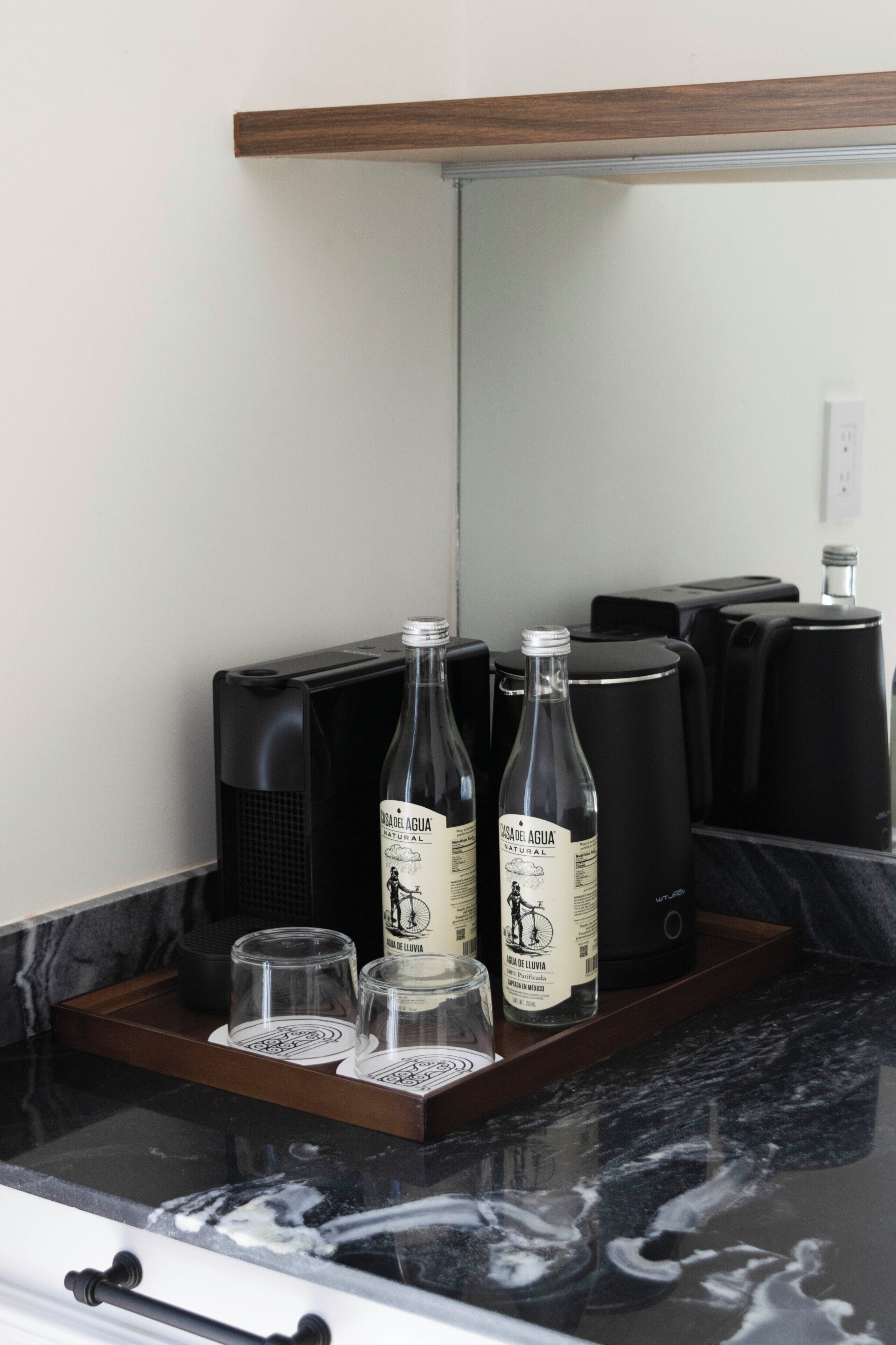 A kitchen counter with a coffee maker, two bottles of water, and three glasses.