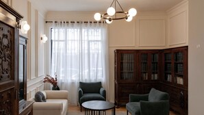 A room with a sofa, armchair, round table, and a wooden bookcase. - Casa Lerma (Mexico City)