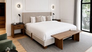 A modern bedroom with a large bed, bedside tables, a bench, and a view of greenery. - Casa Lerma (Mexico City)