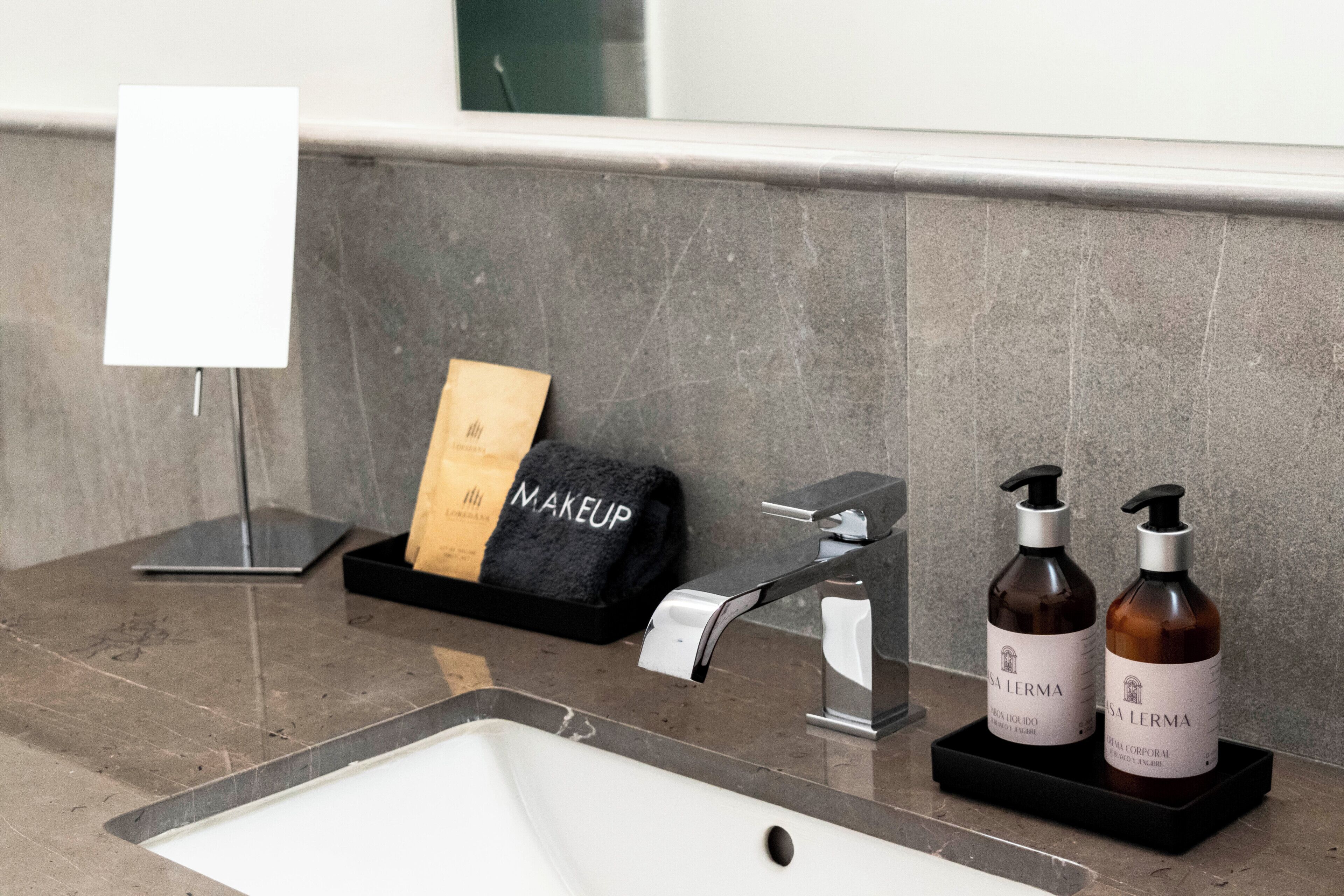 A bathroom with a sink, a towel rack, and two bottles of lotion.