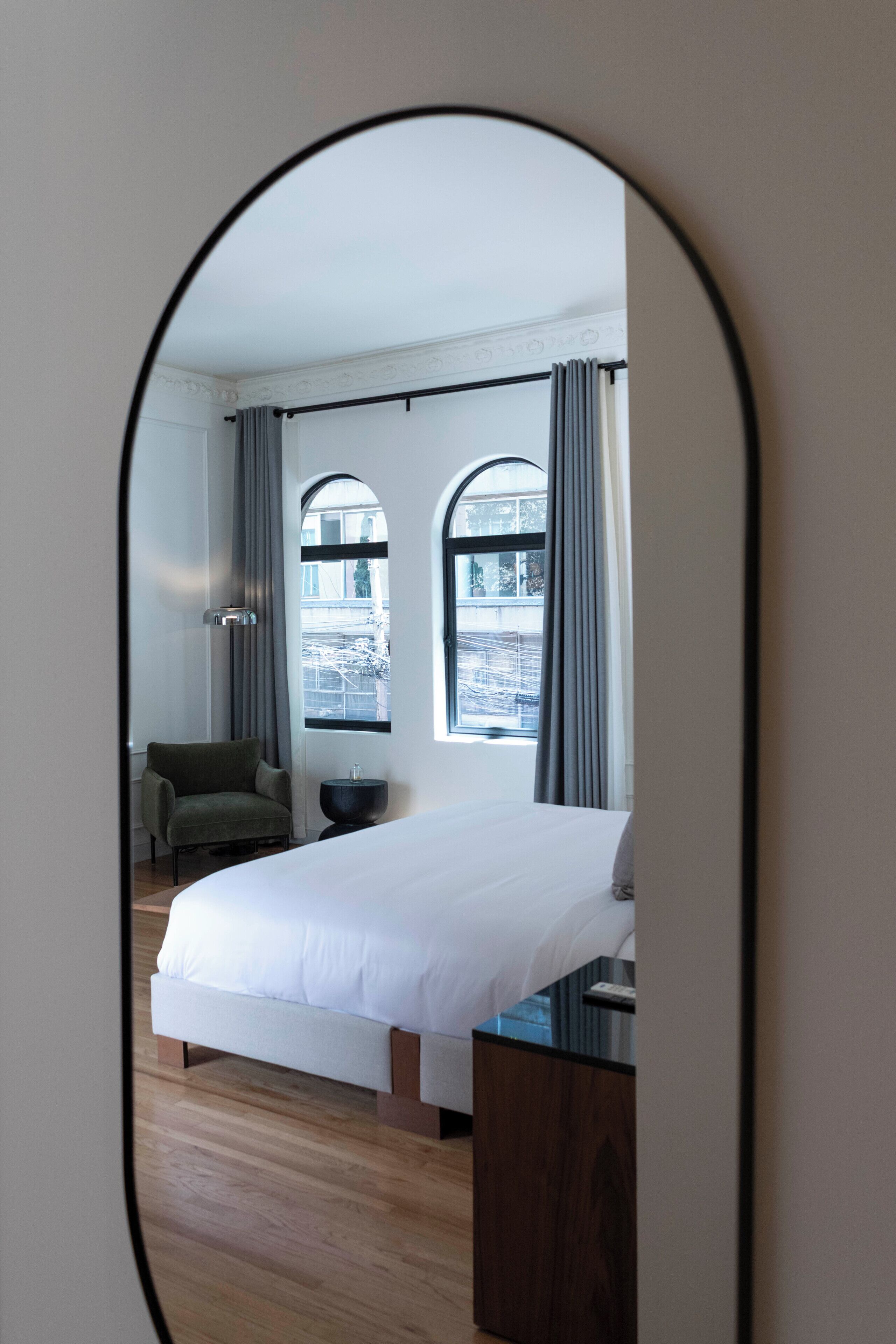 Un dormitorio con cama, una silla, una mesita de noche y una ventana con cortinas.