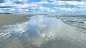 A beach with a wide sandy shore and gentle waves, under a partly cloudy sky. - Sunsets on Sealoft by Sandpiper | Near Beach (Seabrook Island)