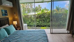 Una camera da letto con un letto, un comodino, una lampada e una porta scorrevole in vetro che dà su un giardino.