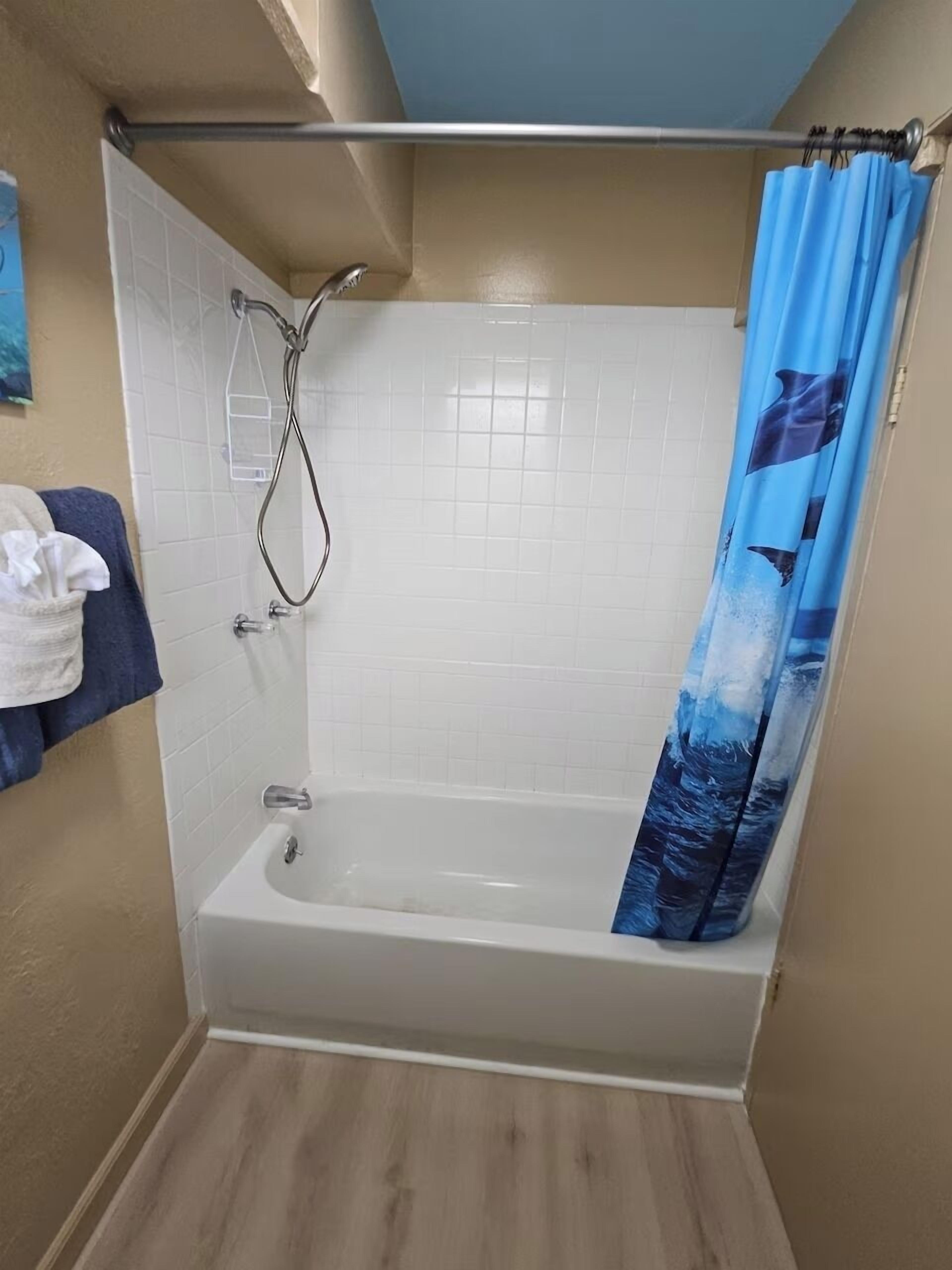 Ein Badezimmer mit Badewanne, Dusche und einem blauen Vorhang.