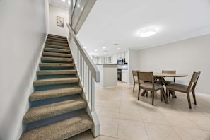 Una escalera conduce a un área de comedor con una cocina al fondo.