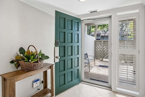 Una puerta verde con una cesta de hojas verdes sobre una consola de madera.