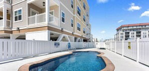 A residential building with a swimming pool, white railings, and a clear blue sky. - Residence 102N at The Sandcastle Condominiums (Wildwood Crest)