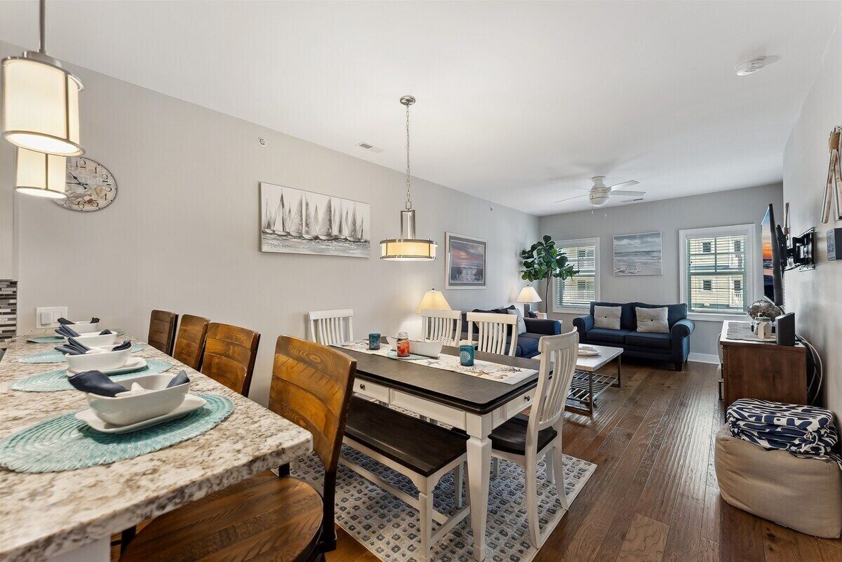 A modern living space with a dining area, a sofa, and a ceiling fan.