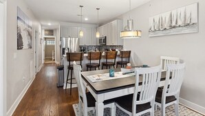 A modern kitchen with white cabinetry, a central island, and pendant lighting. - Residence 102N at The Sandcastle Condominiums (Wildwood Crest)