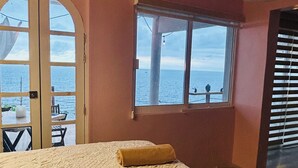 A room with a bed, a window with a view of the sea, and a door leading outside. - Oceanfront Villa-Stunning Sunsets ! (Aguacate)