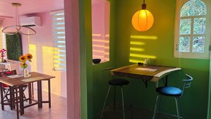 A room with a wooden table, two bar stools, a hanging light fixture, and a window with blinds. - Oceanfront Villa-Stunning Sunsets ! (Aguacate)