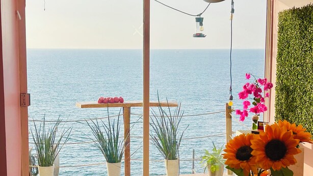A room with a view of the sea, a table with a vase of sunflowers, and a hanging light fixture. - Oceanfront Villa-Stunning Sunsets ! (Aguacate)