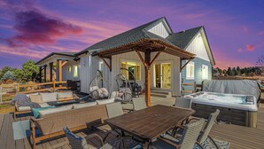 A deck with outdoor furniture, a hot tub, and a covered patio area. - 5 Bedroom house with amenities galore! Oversized hot tub, outdoor fire pit, smoker and propane grill, sauna, play set, espresso machine, air hockey table, indoor fireplace in both living rooms, and legacy bar. (Colorado Springs)
