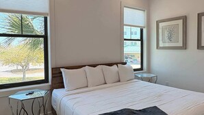 A bedroom with a bed, two windows, a ceiling fan, and a small table. - Coastal home near beaches and shopping (Port St. Joe)