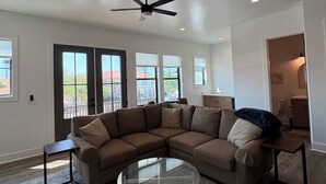 A living room with a sectional sofa, a glass coffee table, and a ceiling fan. - Coastal home near beaches and shopping (Port St. Joe)