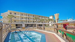 Un hotel con piscina, varios balcones y palmeras.