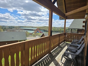 Eine Holzterrasse mit Stühlen, Blick auf Gebäude und bewölkter Himmel.
