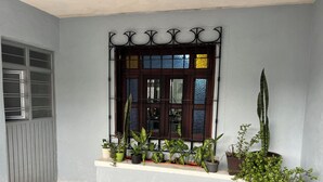 Ein Fenster mit einem Metallgitter, einem Steinfußboden und Blumentöpfen auf einem Sims.