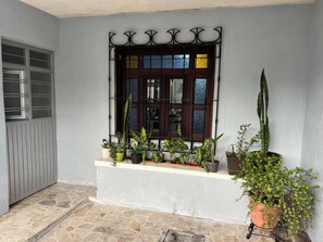 Ein Fenster mit einem Metallgitter, einem Steinfußboden und Blumentöpfen auf einem Sims.